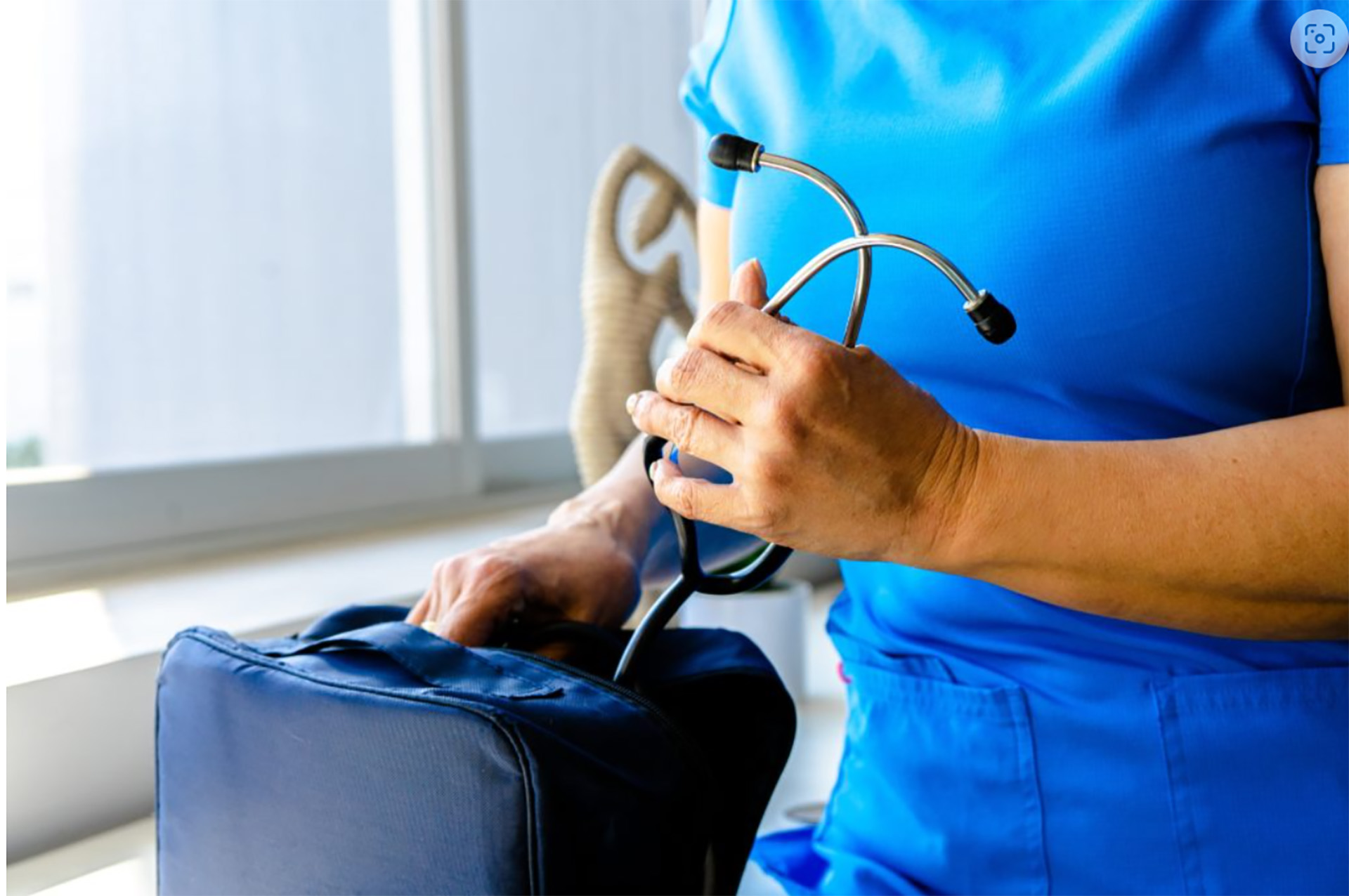 a woman in a blue scrub suit holding a stethoscope