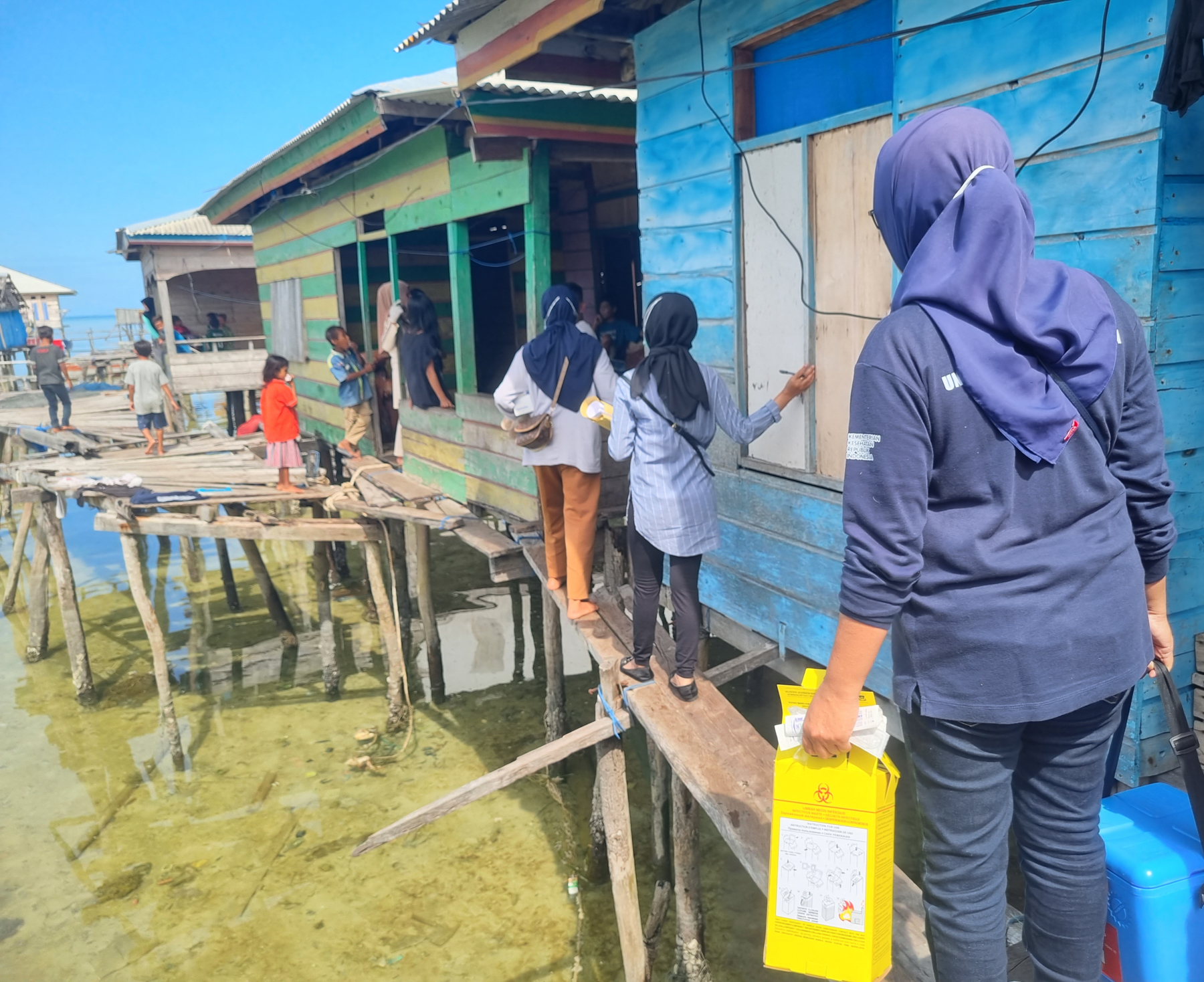Health care workers conducting home visits to stilted houses in Pasikuta Island.